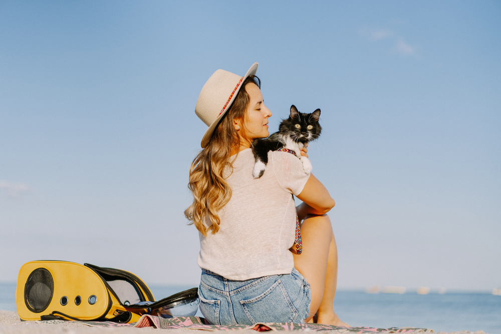 Young woman with a cat and backpack near the beach