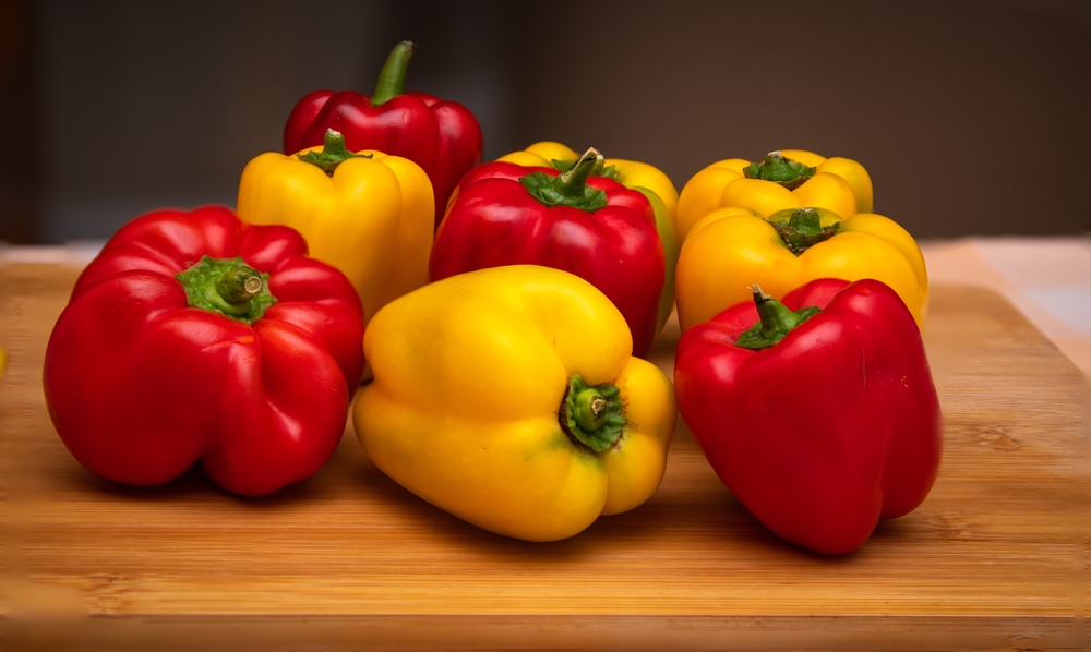 assorted red and yellow bell peppers placed on a cutting board in the kitchen
