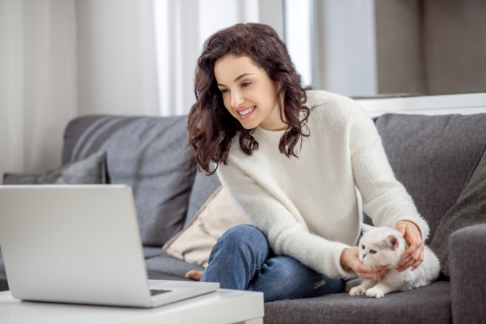 woman working on her laptop with her cat on the couch